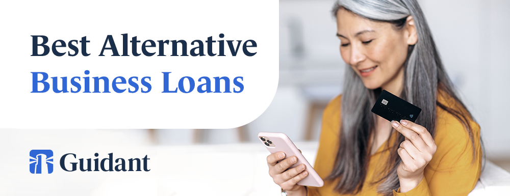 Best alternative start up business loans Shows an older woman holding a credit card and browsing her phone, smiling.