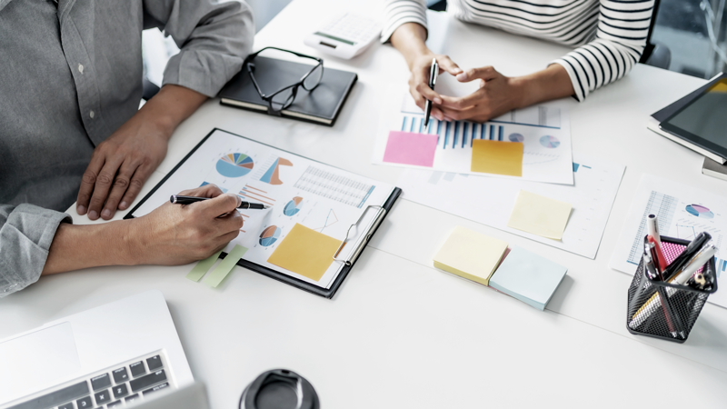 Two people at a desk with paperwork, performing a small business valuation. 