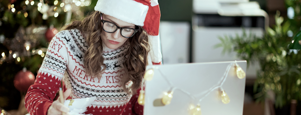 Reduce holiday stress and business owner stress with these strategies. Header image shows a woman dressed festively, working at her desk and looking stressed.