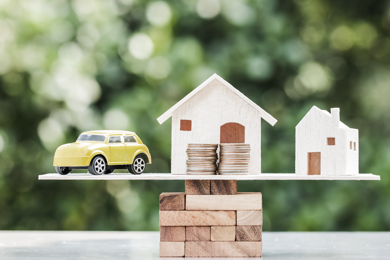 (Unsecured loans can be great start up business loans because you don't have to sacrifice your house or car as collateral.) Photo shows a balance with a wooden house model, toy car, and coins. 