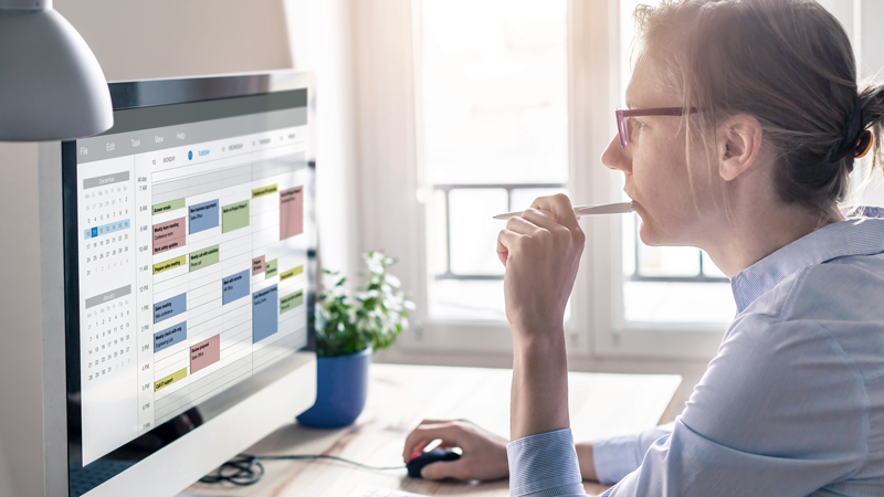 Businesswoman using time blocking on her desktop computer and digital calendar. 