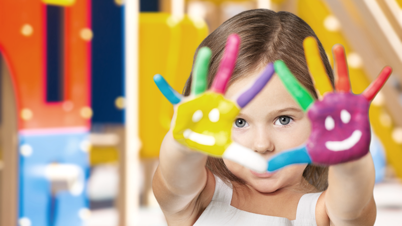 A little girl holds up two painted hands, which count the number ten for the 10 Top Childcare Franchises of 2022. 