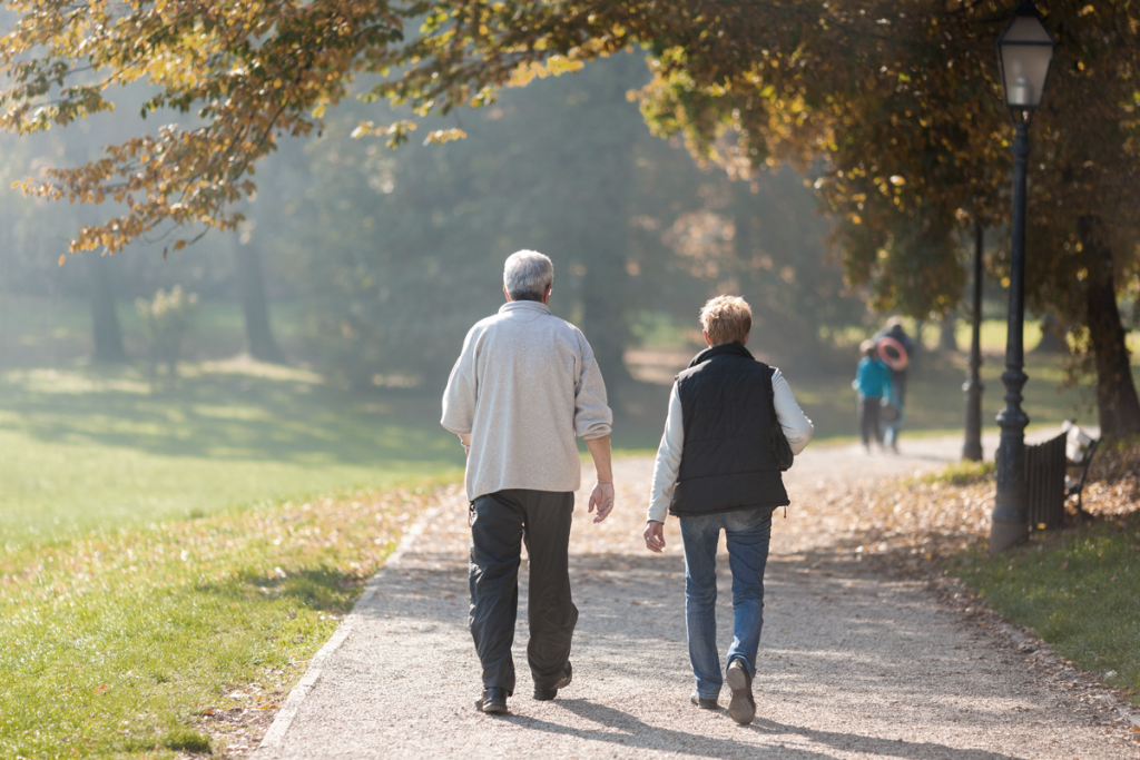 A couple walking on a trial with leaves falling. (How to reduce small business stress blog.) 