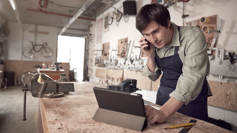 Male small business owner in his bicycle shop looking at a tablet (Blog: Small Business Week, Big Dreams: How to Find and Secure Business Financing)