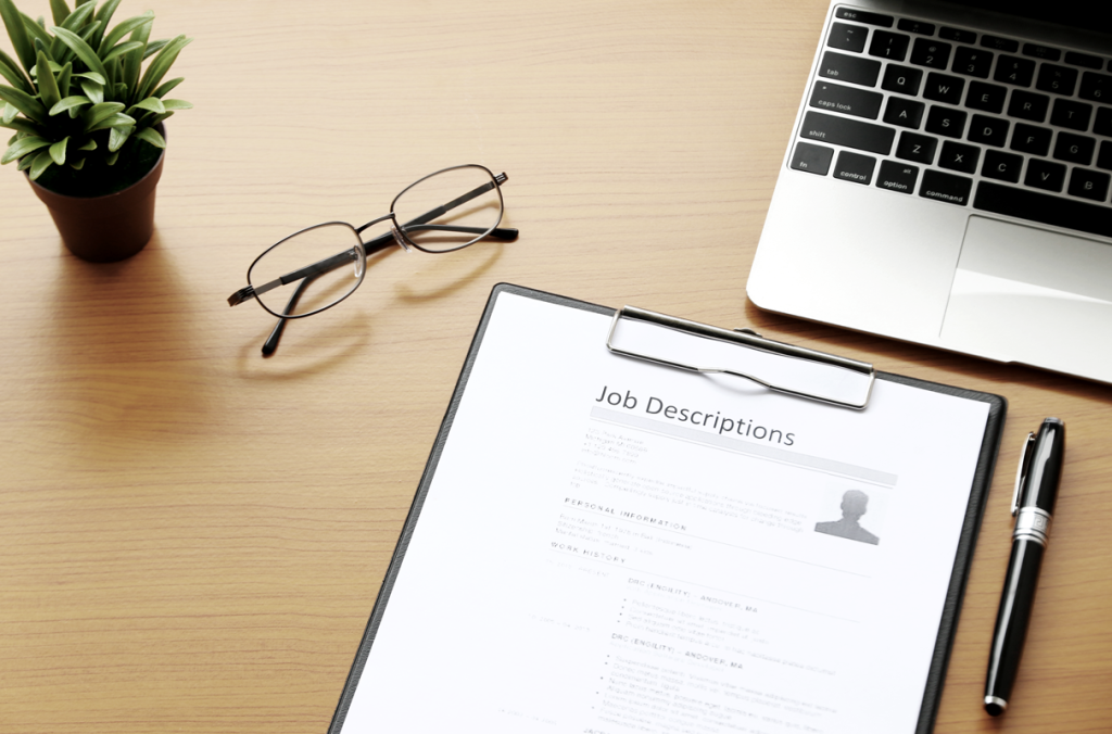 Image of a clipboard holding a job description paper on a desk. (Hiring for Small Business 101: When and How to Find the Right Talent - Guidant Blog). 