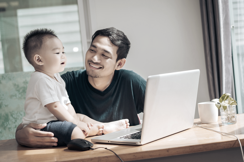 Man working remotely at his desk with his son. (Top Remote Work Tips for Staying Connected and Efficient — Guidant Blog.)