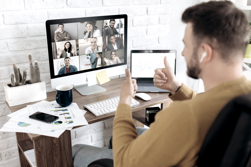 Man working at his desk with two computers on a Zoom call meeting (Top Remote Work Tips for Staying Connected and Efficient — Guidant Blog.)