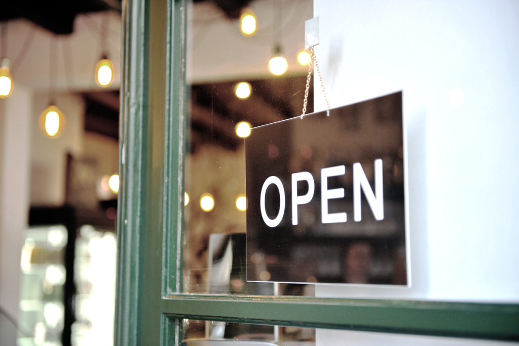 An "Open" sign displayed outside of a  green storefront door. (Top Franchise Industries and Industry Trends - Guidant Financial Blog.)