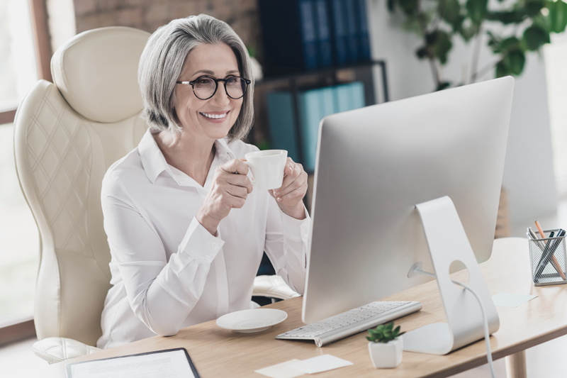 Woman enjoying hot beverage in mug at desk while looking at the computer screen. (Top Remote Work Tips for Staying Connected and Efficient — Guidant Blog.)