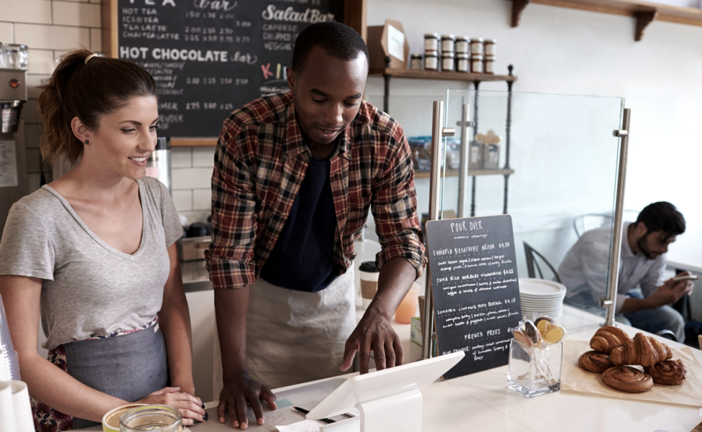 Business owner in cafe training employee on system. (Tips on How to Run Your Small Business on Summer Vacation - Guidant Blog.)