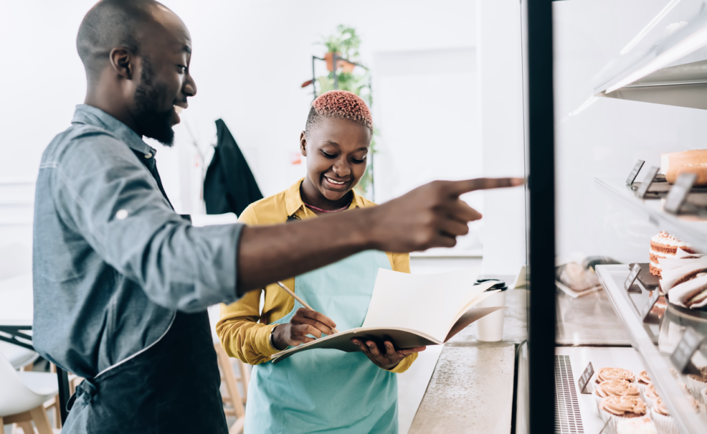 Business owners at a bakery looking at a display case while in conversation. (7 Best Options for Small Business Funding - Guidant Blog). 