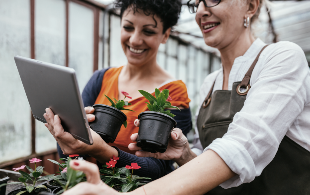 Two older women partnering together, holding plants and looking at a tablet. (Boost Your Small Business with the Power of Hockey Stick Growth in 7 Steps - Guidant).