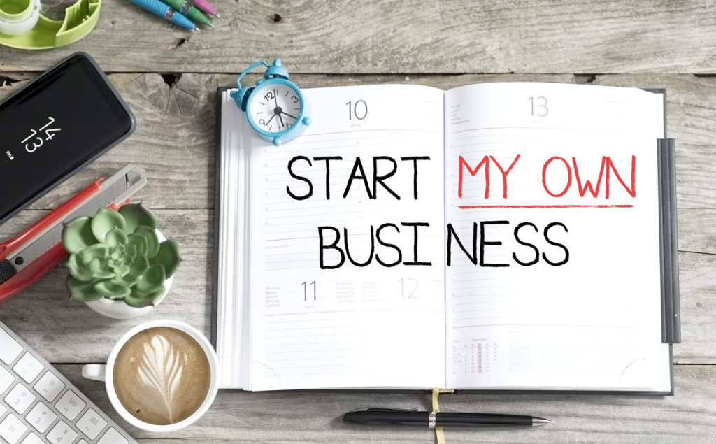 Planner book open reading "Start my own business" in bold, all-cap lettering on a desk with coffee and other office tools. (Transitioning from Office to Entrepreneurship: How to Start a Business with these Top 3 Startup Strategies - Guidant Blog.)