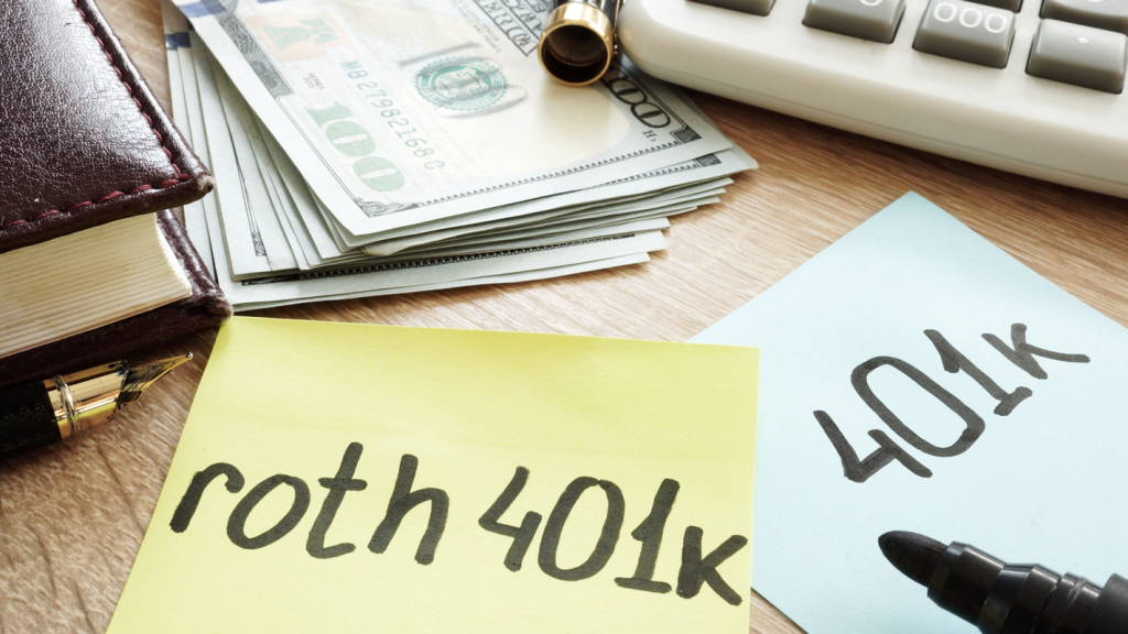 Roth 401(k) and 401(k) written on sticky notes on a desk next to a journal, pens, calculator, and cash. (Demystifying Top Heavy 401k Plans: What You Need to Know - Guidant Blog.)