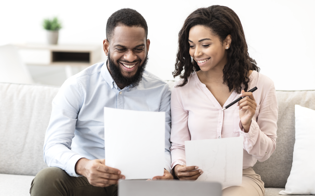 Happy couple looking over paperwork together on the couch. (Your Exiting ROBS Strategy 6-Step Guide - Guidant Financial Blog)