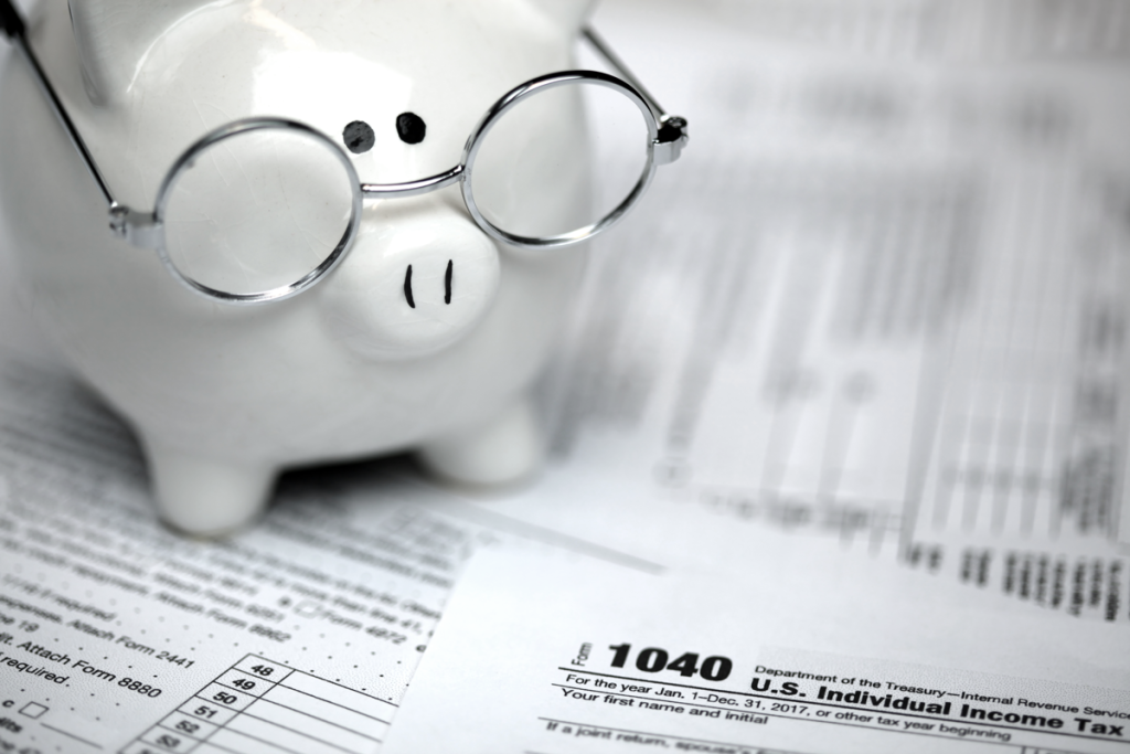 Piggy bank wearing glasses sitting on top of IRS and tax paperwork. (Your Exiting ROBS Strategy 6-Step Guide - Guidant Financial Blog)