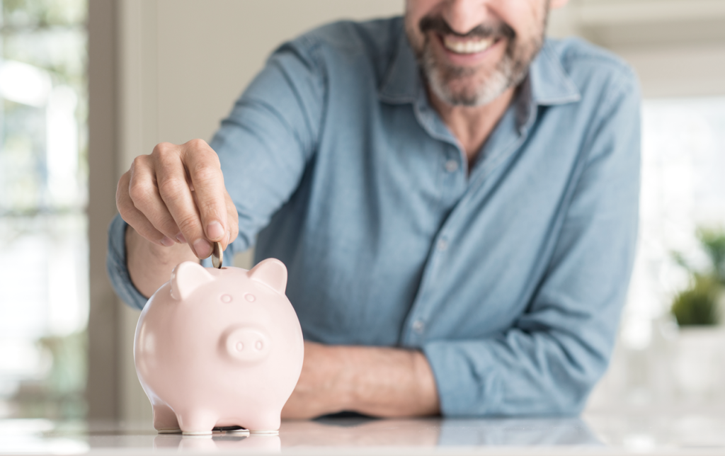 Man putting money in piggy bank while smiling. (Your Exiting ROBS Strategy 6-Step Guide - Guidant Financial Blog)
