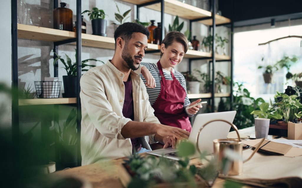 Man and woman shop assistants with laptop working in indoor potted plant store, small business concept. (How To: Small Business Marketing for the Holidays - Guidant).