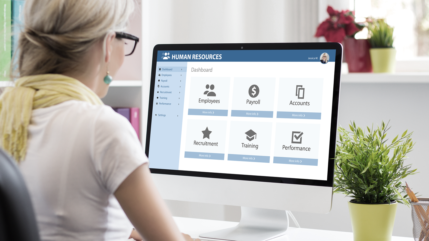 Woman at desk looking at employee information on a desktop. (Complete Guide to Payroll for Small Businesses - Guidant Financial.)