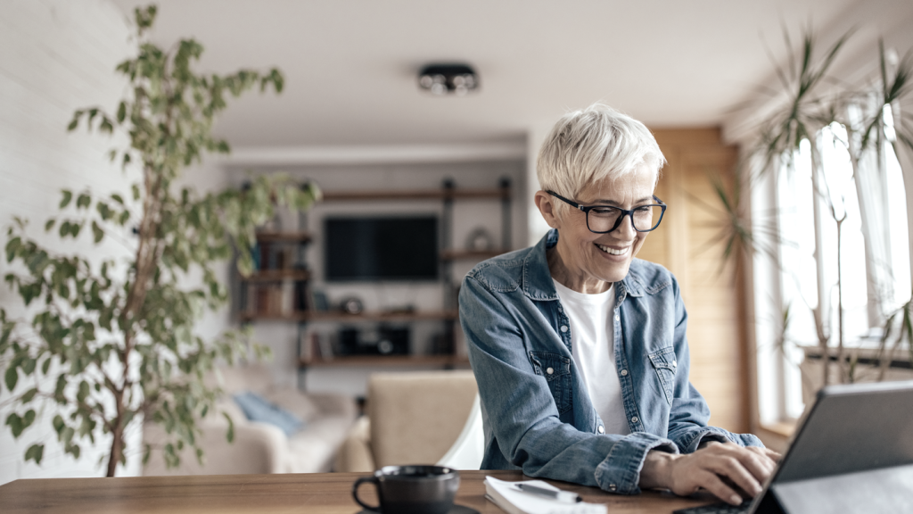 Older woman with glasses completing her taxes on a tablet while smiling. (From Deductions to Deadlines: Your Guide to Mastering Taxes for Small Businesses - Guidant Blog).
