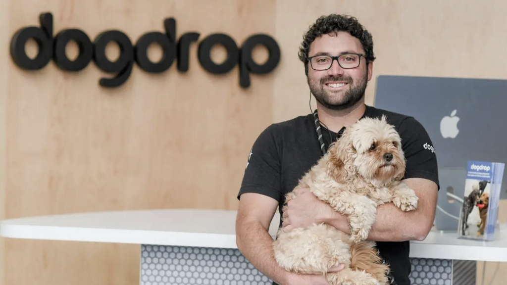 Happy man holding a dog inside a Dogdrop store. (Hottest Pet Care Franchises - Guidant Financial Blog).
