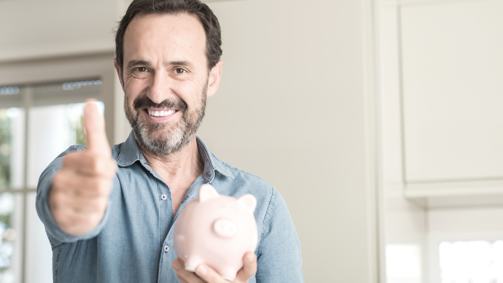 Man pointing while holding piggy bank, smiling. (Maximizing Your Retirement: ROBS Investment Insights - Guidant Blog).