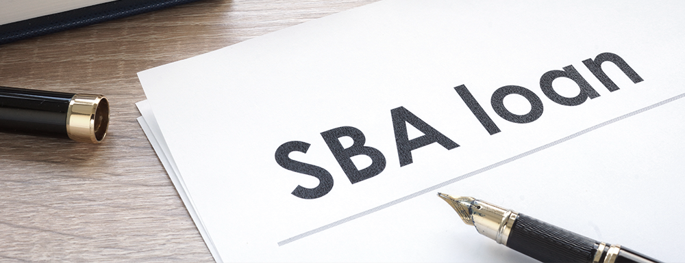 "SBA Loans" written on paper next to a pen. (SBA Loan Requirements: Top 6 SBA Loan Deal Breakers - Guidant Blog)