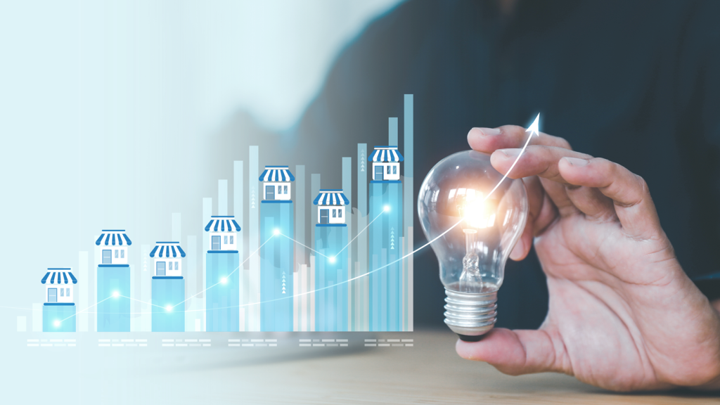 Graphic showing franchise buildings growing on a chart next to a hand holding a light bulb. (Is Franchising Right For You? - Guidant Blog).