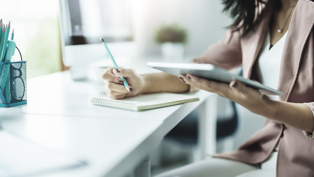 Woman planning with tablet and notepaper on desk. (7 Common Business Pitfalls and How to Avoid Them - article by Jeremy Ames)