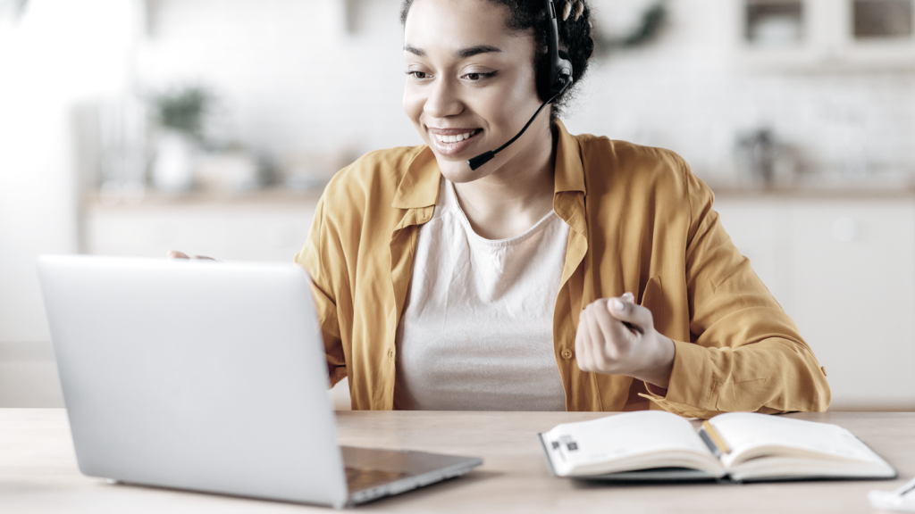 Woman on her laptop smiling with headphones. (7 Creative Health and Wellness Business Ideas - Guidant Blog)