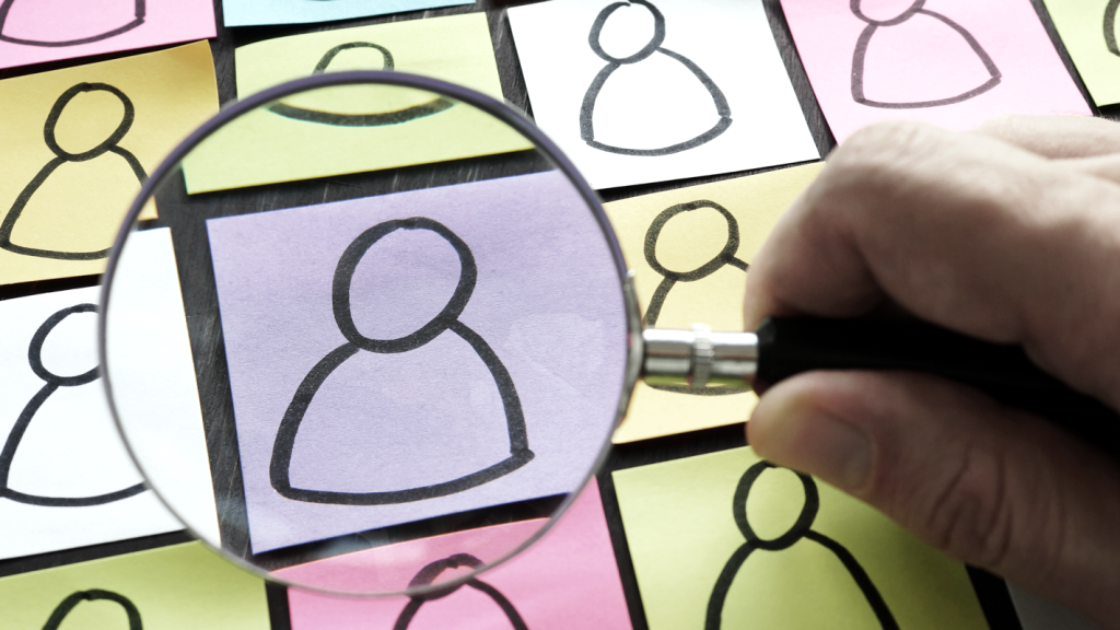 Sticky notes with people drawn on them and a magnifying glass highlighting one of them. (How to Start an Art Business: Complete Guide - Guidant Blog.)