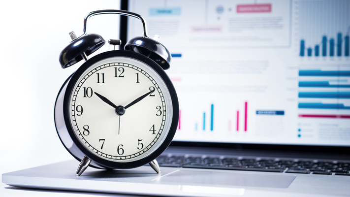Clock sitting on a laptop with data on the screen in the foreground. (7 Common Funding Small Business Mistakes - Guidant blog)
