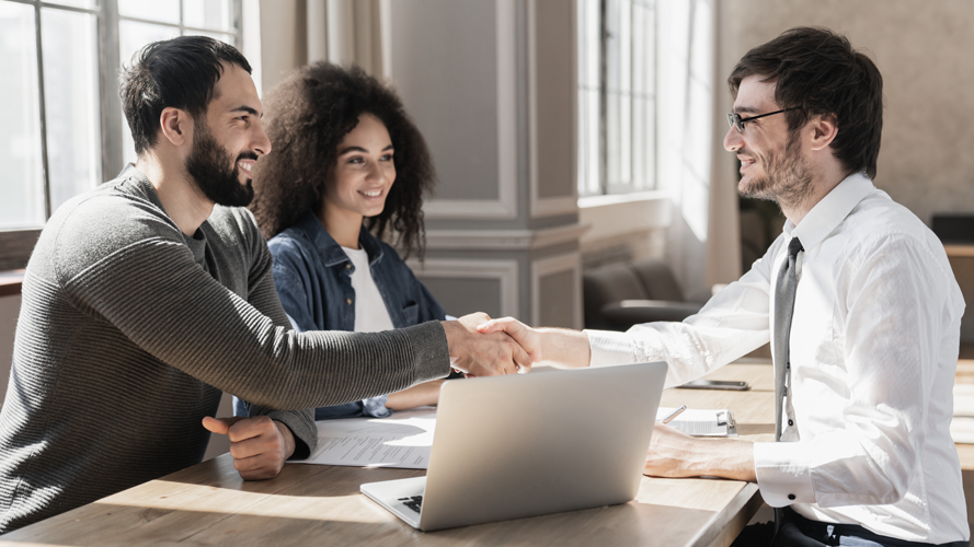 Couple meeting with potential lender and shaking hands, smiling. (How to Create a Winning Business Financial Strategic Plan - Guidant Blog.)