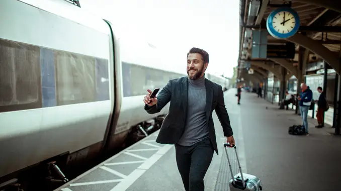 Man happily on his way to make the train with a suitecase. (Top Tourism Industry Trends and Top Travel Industry Trends - Guidant Financial.)