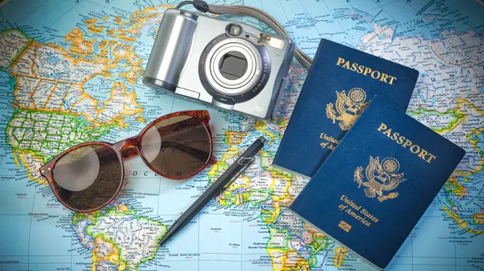 A still life showing a camera, sunglasses, and passports on a world map. (Top Tourism Industry Trends and Top Travel Industry Trends - Guidant Financial.)