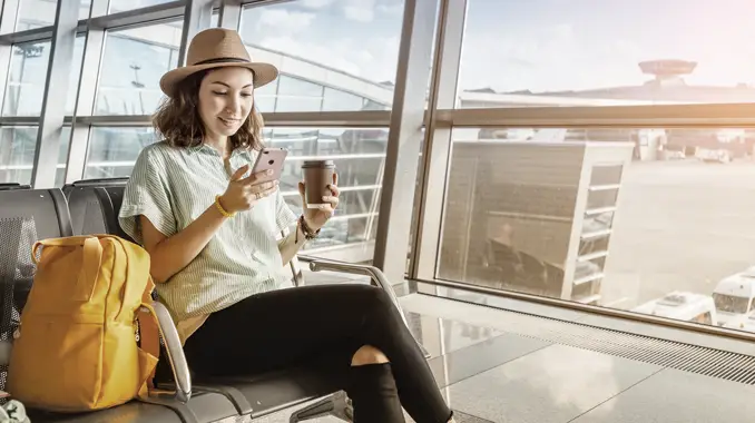 Woman on her phone in an airport setting. (Top Tourism Industry Trends and Top Travel Industry Trends - Guidant Financial.)