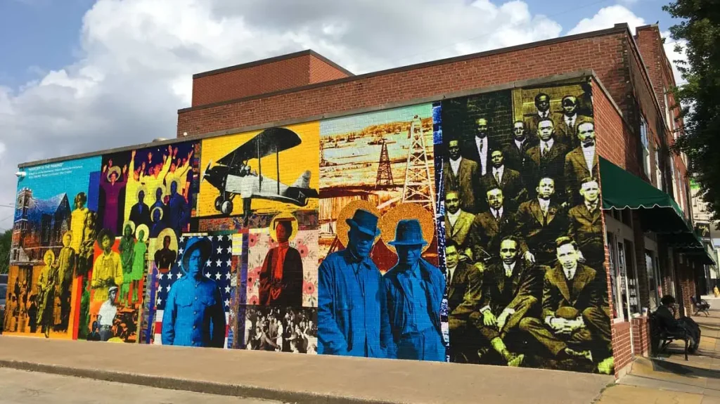 The vibrant "History in the Making" mural by Skip Hill on the side of 111 N. Greenwood Ave, showcasing Greenwood's pioneers. Image from Tulsa Tours. Guidant Blog - Exploring the Legacy of Black Wall Street Today